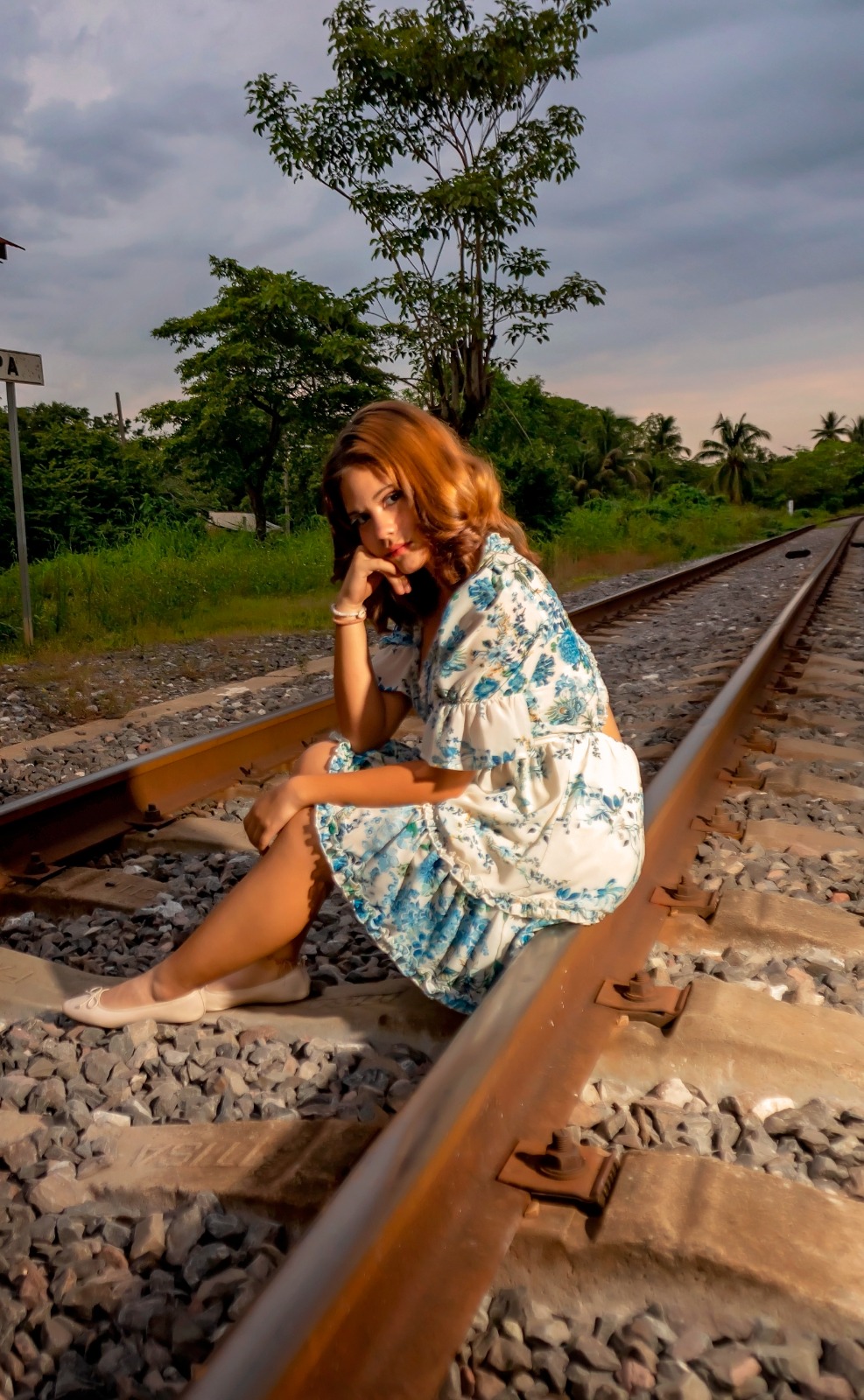 Antonella sentada en las vías del tren al atardecer